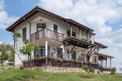 a large white house with a balcony at Balkana Village in Kalaydzhii
