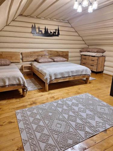a attic room with two beds and a rug at Шепіт Карпат 2 in Synevyrsʼka Polyana