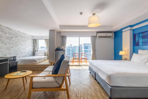 a hotel room with two beds and a couch at Journeyhub Pattaya Central in Pattaya
