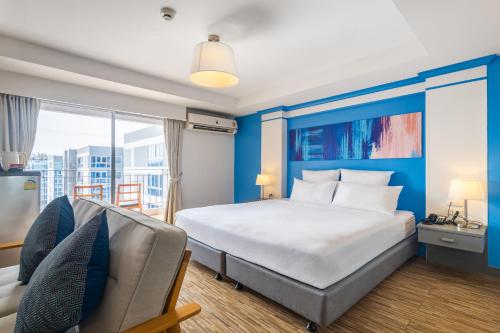 a bedroom with a large bed and a couch at Journeyhub Pattaya Central in Pattaya