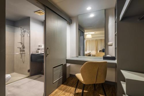 a bathroom with a chair and a sink and a mirror at Journeyhub Pattaya Central in Pattaya