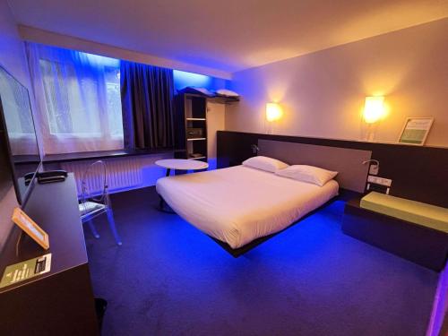 a hotel room with a bed in a blue room at ibis Styles Lorient Caudan in Caudan