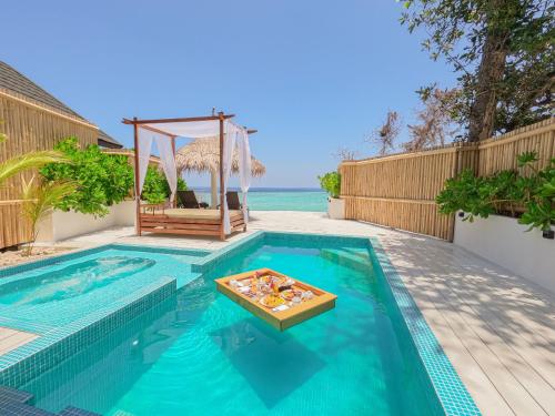 a swimming pool with a table in the middle at Malahini Kuda Bandos Special Offer Begin your island escape with ease airport pick up and return by shared speedboat at just USD 50 per person stays stay untill end October 2026 in North Male Atoll