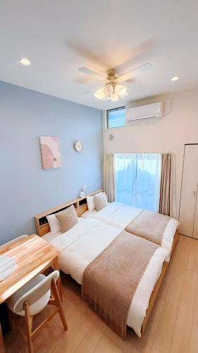 a bedroom with two beds and a table and a ceiling fan at Le Amo吉塚 in Fukuoka