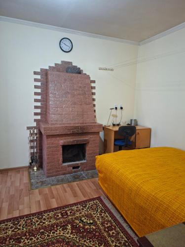 a bedroom with a brick fireplace with a clock on the wall at Садиба в Бабаєво in Perechin
