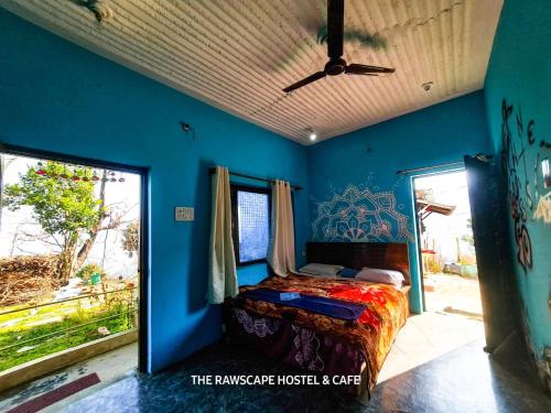 a bedroom with a bed in a blue wall at The Rawscape Hostel in Kausani