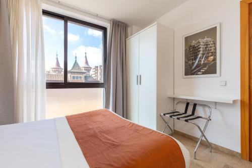 a bedroom with a bed and a window and a chair at Picasso Suites in Barcelona