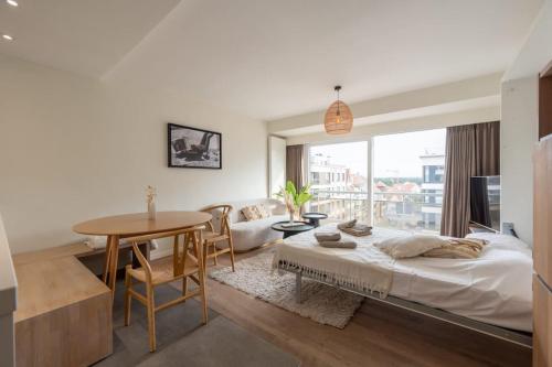 a bedroom with a bed and a table and a dining room at Modern Cozy Studio - Prime location Knokke in Knokke-Heist