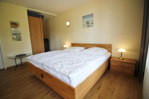 a bedroom with a large bed with white sheets at Golfresidenz B 109 in Grömitz
