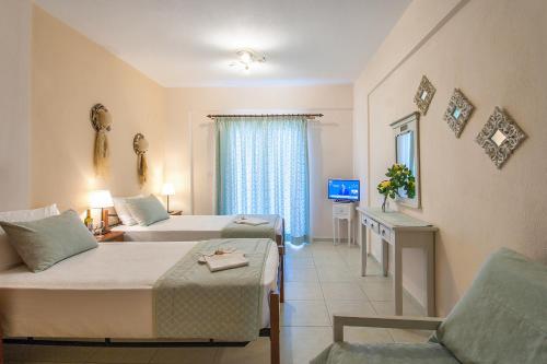 a hotel room with two beds and a chair at Syrainas studios in Troulos