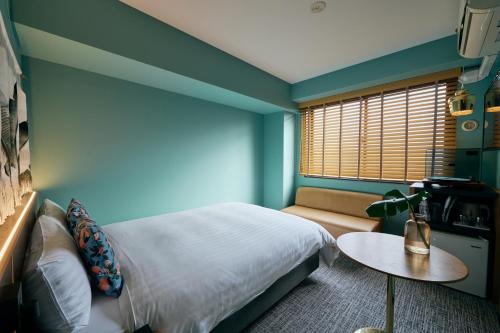 a bedroom with a bed and a table and a window at Hotel She, Kyoto in Kyoto