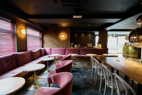 a restaurant with a red couch and tables and chairs at Hotel She, Kyoto in Kyoto