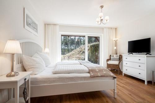 a white bedroom with a bed and a window at Golfresidenz B 010 Heimathafen in Grömitz