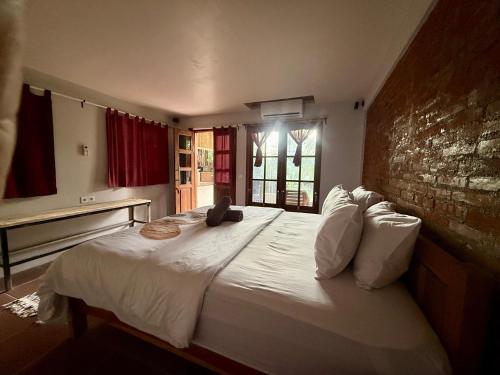 a bedroom with a large white bed with a brick wall at Lombok House Mentigi in Teluknarat