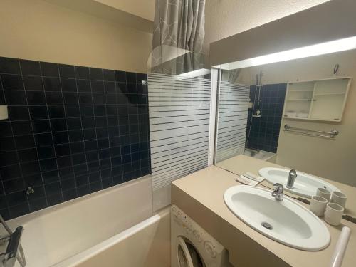 a bathroom with a sink and a mirror and a tub at Appartement - Bonamour in Capbreton