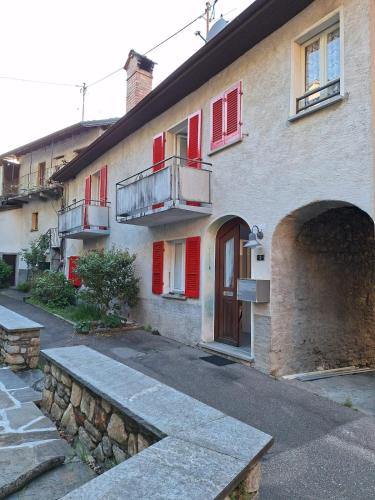 a building with red shutters and a building with a bench at Ferienhaus in Piazzogna in Gambarogno
