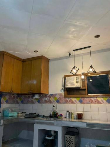 a kitchen with wooden cabinets and a microwave at Cebu Cozy Affordable Transient Room Wifi Netflix Shower Heater in Cebu City