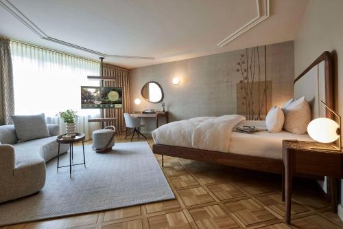 a bedroom with a bed and a living room at Parkhotel Gütersloh in Gütersloh