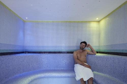a man sitting in a tub in a bathroom at Parkhotel Gütersloh in Gütersloh