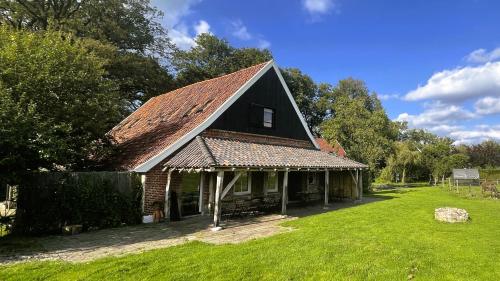 an old house with a brown roof on a yard at 't Buitenverblijf Erve Punte in Losser