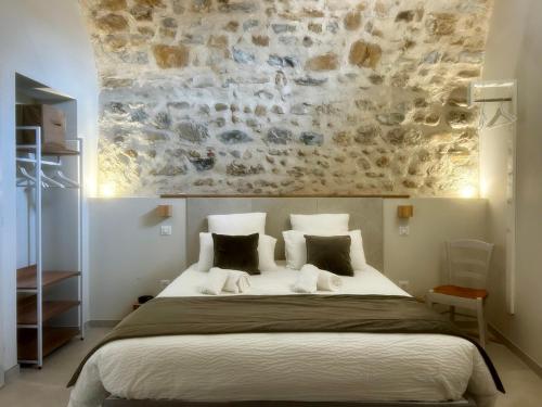 a bedroom with a large bed with a stone wall at Clos des Mouliniers - Gîtes 5 étoiles en Ardèche in Saint-Privat