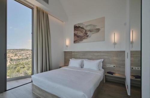 a bedroom with a large bed and a large window at Teria Collection in Porto Heli
