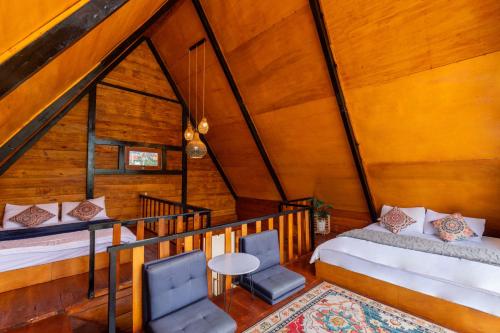 a attic room with two beds and a table and chairs at Cabin Linggayoni dieng in Diyeng