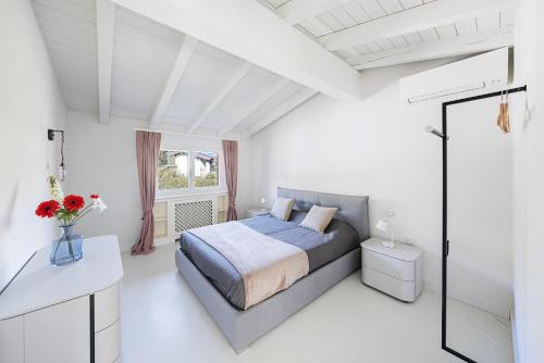 a white bedroom with a bed and a window at Bellavista by Whale Homes in Padenghe sul Garda