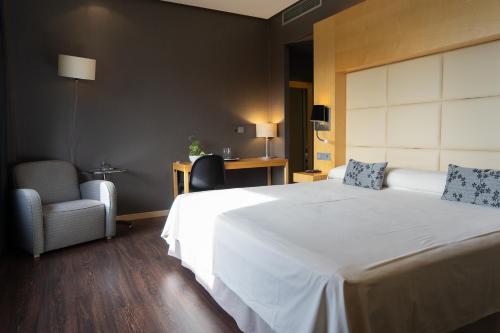 a bedroom with a large white bed and a chair at Los Claustros de Ayllón in Ayllón