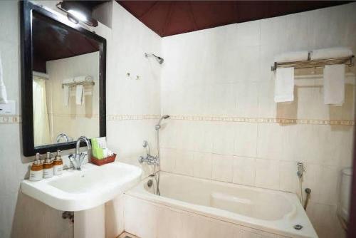 a bathroom with a sink and a tub and a mirror at The Heritage Kochi in Cochin