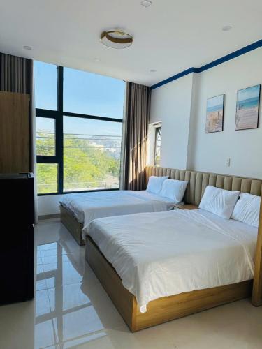two beds in a bedroom with a large window at Lighthouse Hotel & Apartment Phan rang in Kinh Dinh
