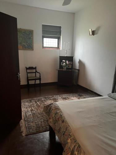 a bedroom with a bed and a chair and a window at Kandy summerhill bungalow in Kandy
