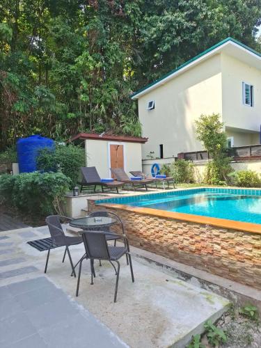 a patio with a table and chairs next to a swimming pool at Private Pool Villa , 4BR, Fast WiFi, BBQ Garden in Ban Dan Mai