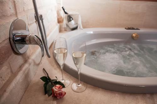 two champagne glasses sitting next to a bath tub at Colle Indaco Wine Resort & Spa in Ortezzano