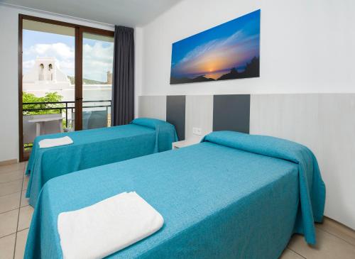 a hotel room with two beds and a window at Apartamentos Tramuntana in San Antonio