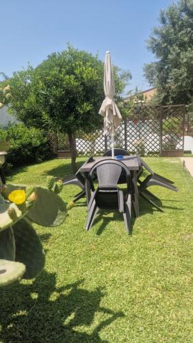 a picnic table with an umbrella on the grass at Le Case Al Quadrato Residence in Syracuse