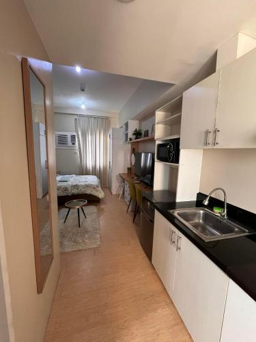 a kitchen with a sink and a room with a bed at Sunvida Tower - Cebu Stay Rental in Dita