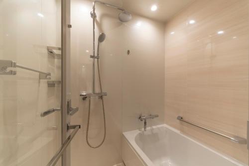 a bathroom with a shower and a tub and a sink at Hotel JAL City Nagoya Nishiki in Nagoya