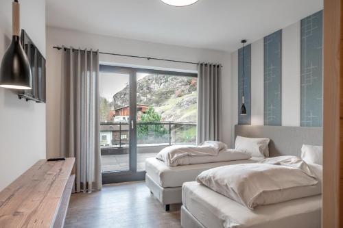 a bedroom with two beds and a large window at Corso Living in Sölden