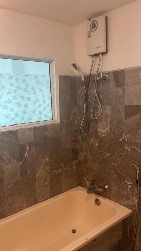 a bathroom with a bath tub and a window at Niruan apartment in Pattaya