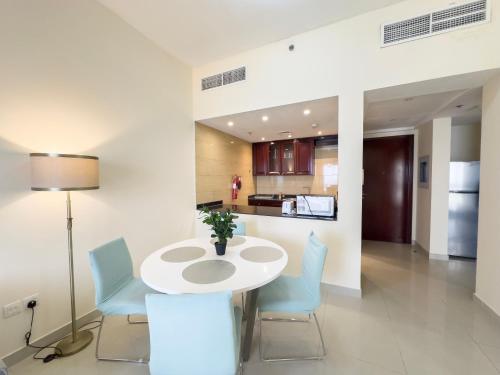 a dining room with a white table and blue chairs at Royal Breeze Sea View One Bedroom Apartment in Ras al Khaimah