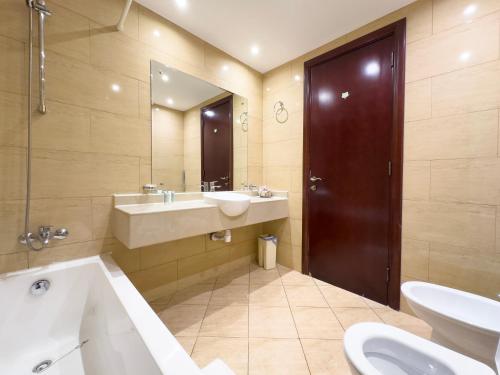 a bathroom with a tub and a sink and a mirror at Royal Breeze Sea View One Bedroom Apartment in Ras al Khaimah