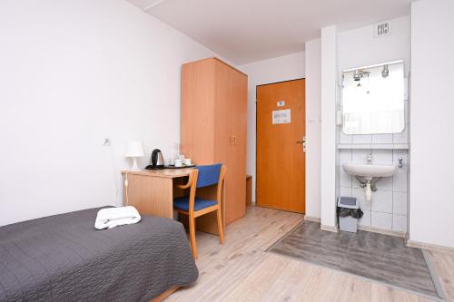 a bedroom with a bed and a sink and a desk at Hotel Dom Polonii in Ostróda