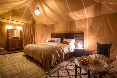 a bedroom with a bed and a table in a tent at Platinum Heritage Desert Camp in Jaisalmer