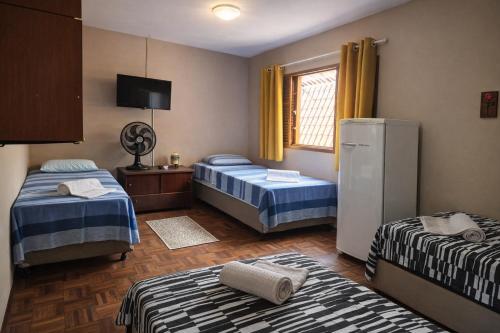 a room with two beds and a refrigerator at CASA 230 - Guest House in Piracicaba