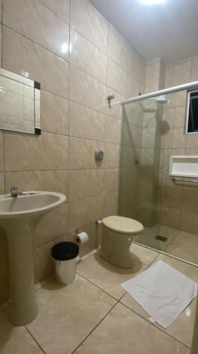 a bathroom with a shower and a toilet and a sink at Simar Hotel in Araranguá