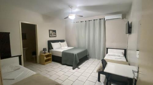 a room with two beds and a desk and a bed at Simar Hotel in Araranguá