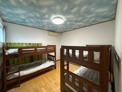 two bunk beds in a room with a ceiling at ゲストハウス輝庵 in Sado