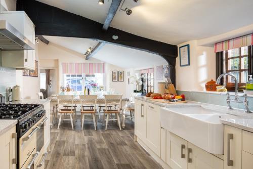 a kitchen with white cabinets and a dining room at The Old Sweet Shop in Minehead
