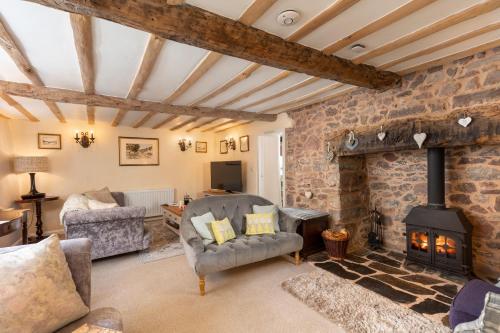 a living room with a stone wall and a wood stove at The Old Sweet Shop in Minehead